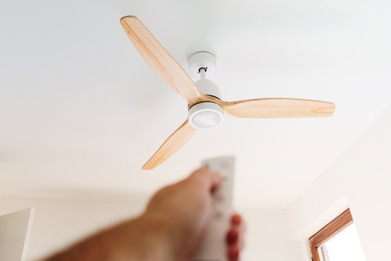 Do I Need an Electrician for Ceiling Fan Installation? A person turning on a ceiling fan.
